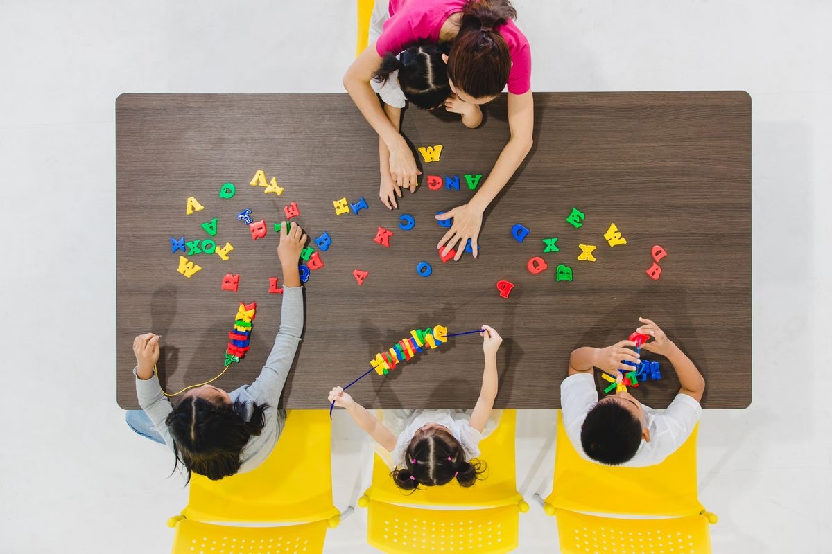 Group of kids and teacher playing colorful toys in classroom. Concept for happy and funny learning, brain development activities in school free time. Group of kids and teacher playing colorful toys in classroom. Concept for happy and funny learning, brain development activities in school free time.